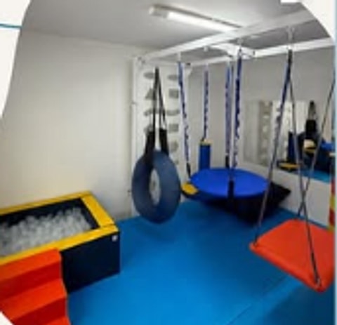 Sala de estimulação motora do Instituto Therapy, com balanços terapêuticos, piscina de bolinhas e piso emborrachado azul.