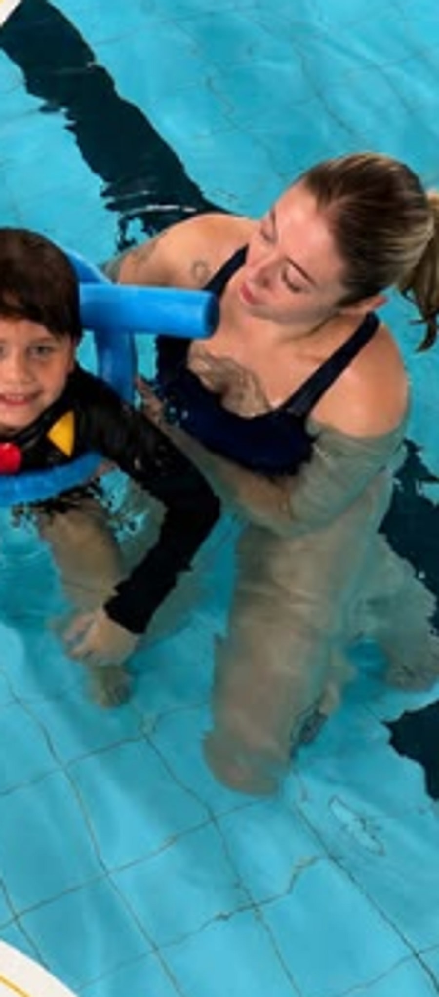 Terapeuta acompanhando criança durante sessão de hidroterapia na piscina do Instituto Therapy.